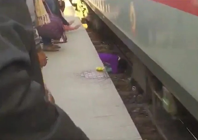 Indian woman shields her 2 children as train speeds past them after they were pushed onto track